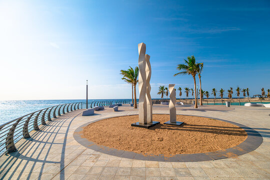 Jeddah, Saudi Arabia - Jan 7, 2025: Jeddah Waterfront Corniche showcasing a contemporary white sculpture, palm trees, and the Red Sea under a bright clear sky