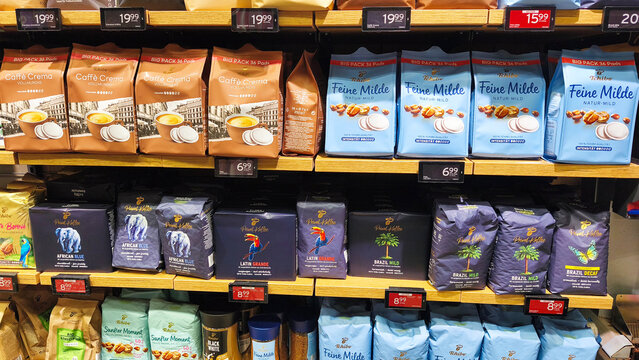 Hagen, Germany &mdash; May 20 2026: packages and pads of Tchibo coffee on wooden shelves inside a Kaufland supermarket in Hohenlimburg.