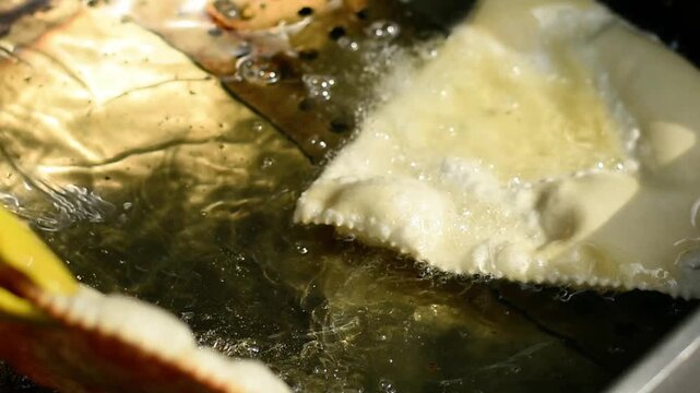 deep-frying concept. Cheburek frying in hot oil, golden pastry sizzling in pan, crispy snack cooking in deep fryer, delicious fried food preparation, closeup of traditional food in oil