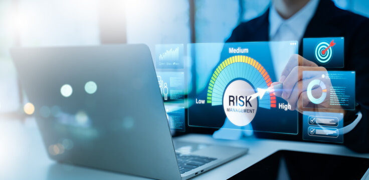 Businessman using laptop with glowing risk meter, data charts and tech icons for identifying, assessing, and mitigating future occurrences.Risk management and business assessment concept