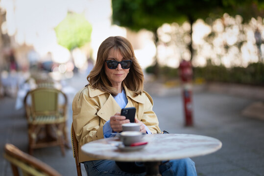 Sophisticated mature woman enjoying morning coffee at a european sidewalk cafe