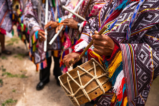 Hands of Andean villagers in traditional costumes playing instruments from the villages of Cusco, Peru