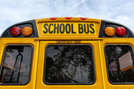Back view of a classic yellow school bus with emergency door and lights