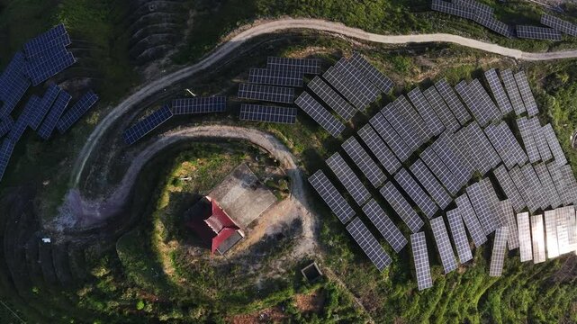 Aerial view of photovoltaic solar panel arrays and transmission towers on a hillside