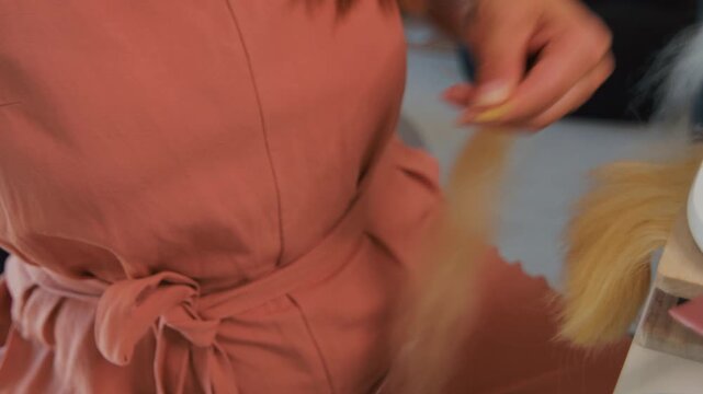 Closeup of a person is preparing hair for extensions by using a heat tool to melt and bond the keratin to the hair