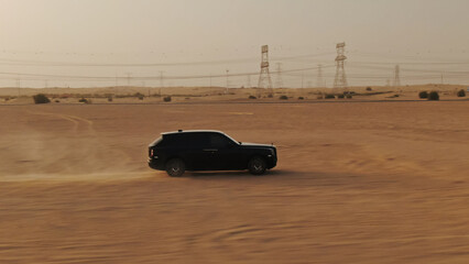 Obraz premium Black luxury suv driving on hot desert sand