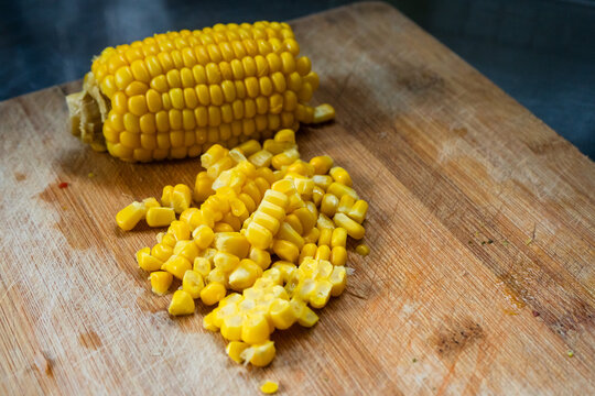 Sweet corn kernels cut from cob on wooden cutting board ingredient for healthy cooking recipe