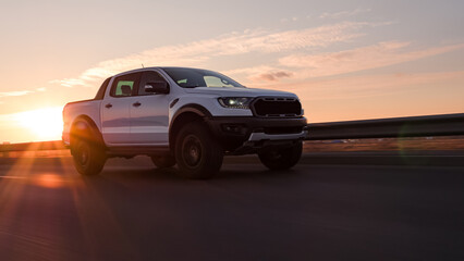 Naklejka premium White pickup truck driving on highway during sunset