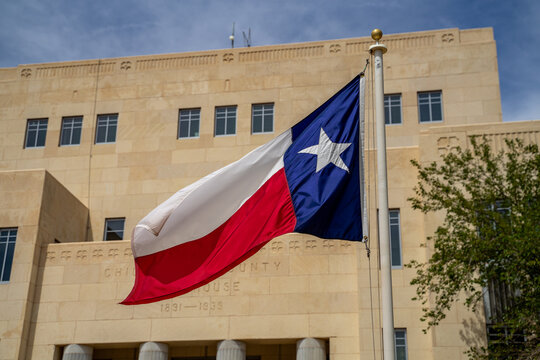 Large Texas Flag Blowing in the Wind in Front of Courthouse Building in Childress, Texas