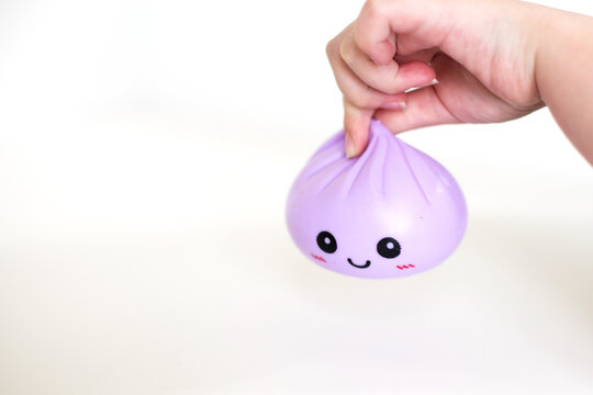 Hand holding purple dumpling stress squishy toy