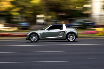 Obraz premium Silver sports car moving fast on city street