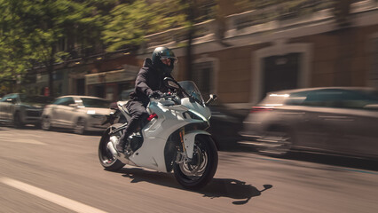 Rider speeding white sport motorcycle on city street © Chris M