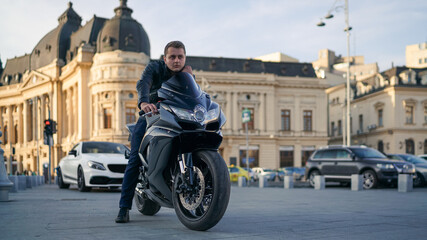 Biker on motorcycle in city square thinking © Chris M