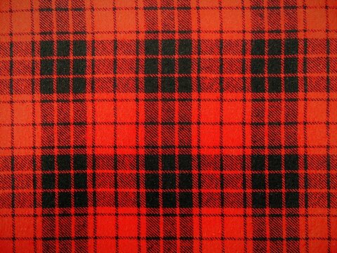 Red and black plaid texture background, traditional Scottish tartan pattern, checkered wool fabric flannel cloth close up.