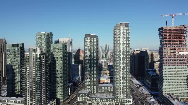 Skyscraper condominiums along Burnhamthorpe Road in downtown Mississauga, Ontario, Canada. Under construction. Aerial, shot with a drone moving right, on a winter afternoon in December, 2021.