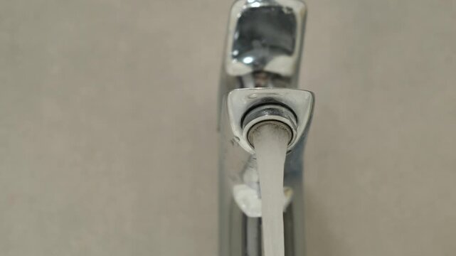 Faucet, water stream, hand turning tap in bathroom, close up on chrome fixture, everyday hygiene and home routine with sink