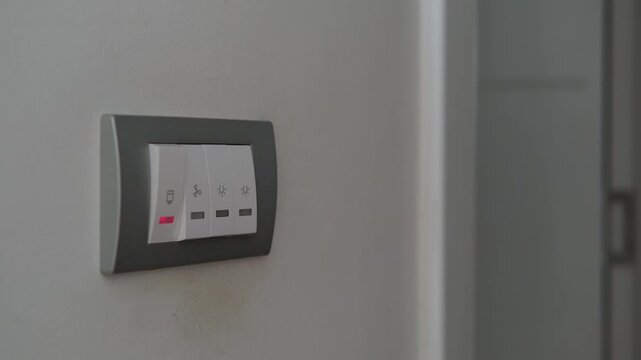 Closeup of a switch panel with four buttons on a neutral wall, highlighting electrical control and device in use