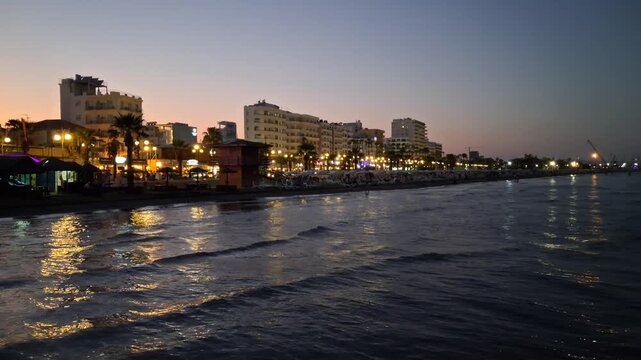 The illuminated buildings alongside Finikoudes beach in Larnaca at dusk.