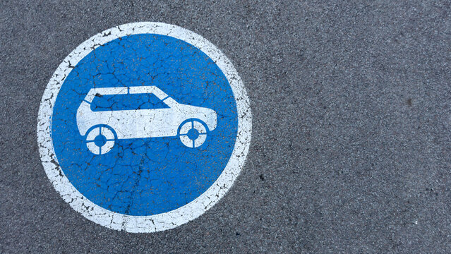 Blue parking symbol for electric vehicles on asphalt surface