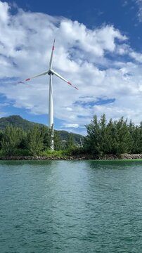 Wind turbines on the island generate clean energy. A working wind turbine against the backdrop of a blue sky and turquoise waters of the Indian Ocean. Mahe Island, Seychelles
