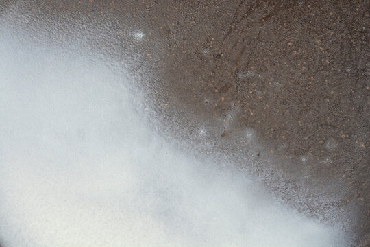 Full frame background texture of creamy white lard melting on a dark metallic surface of a frying pan during cooking