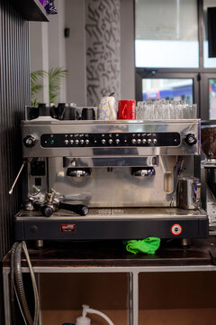 Varna. Bulgaria. 21.05.2026  professional two group espresso machine on bar counter with cups glasses and nescafe mug on top in modern barbershop interior with graffiti wall