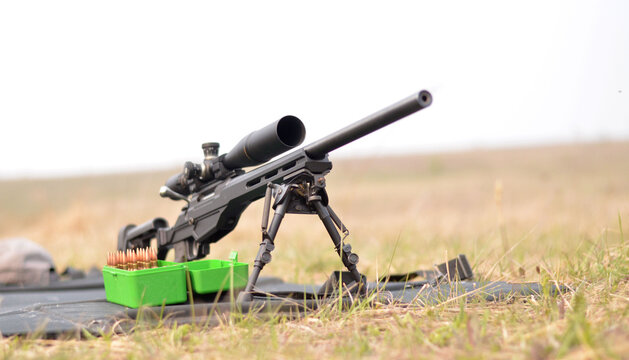 Front view of precision bolt-action rifle with ammunition box on outdoor shooting range