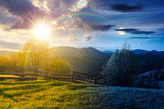 day meet night in mountainous rural landscape in spring. epic view of valley fields at twilight. sun and moon over alpine meadow. carpathian mountains countryside with forest near pasture. harmony