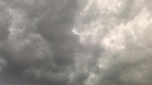 Heavy clouds fill the sky as a storm begins. Dark shades cover the atmosphere. The weather changes quickly, suggesting rain and lightning are on the way. People may seek shelter soon.