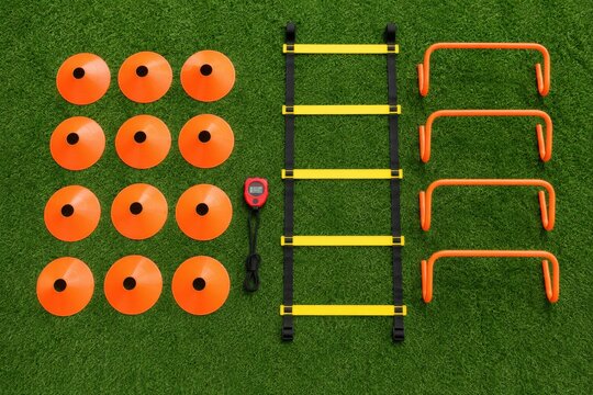 Assortment of soccer training equipment including cones, hurdles, and an agility ladder on turf