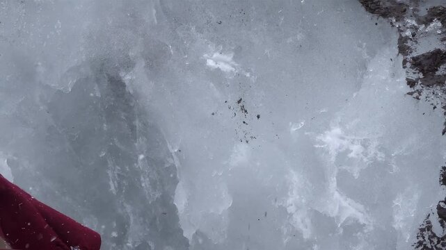 Ice climbing with an ice axe, breaking through frozen ground and ice formations