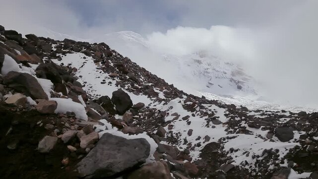 Snowy mountain slope with rocks and clouds, a challenging alpine environment