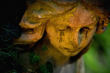 Fototapeta premium Weeping angel statue with tears in warm mystical light