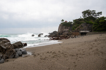 Obraz premium Scenic view of crashing waves at Katsurahama Beach with a cliffside shrine, Kochi, Japan