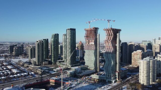 Skyscrapers under construction of downtown Mississauga, Ontario, Canada city centre. Aerial, shot with a drone moving right, on a winter afternoon with snow in December, 2021.