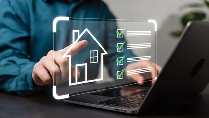 Fototapeta premium Hand holding digital house icon over laptop with real estate interface on screen