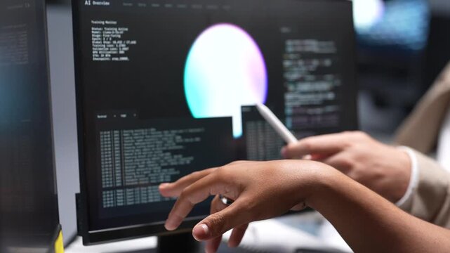 Close up view of tech specialists using a stylus to analyze software source code lines and digital interface graphic elements on a desktop computer monitor.
