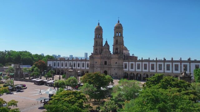 Basilica of Our Lady of Zapopan Featuring a Cinematic Aerial Drone Push In Flight Over the Entrance Avenue and Public Square under a Clear Blue Sky in Jalisco Mexico