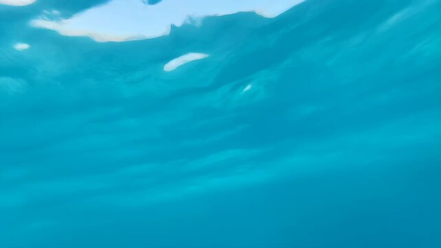 Waves underwater with sunlight creating caustic patterns and reflections featuring blue, water, ocean with light and ripples elements for nature,