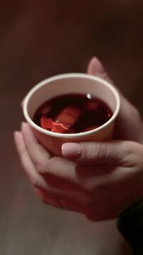 Close Up Hands Holding Hot Mulled Wine Cup in Winter Christmas Market
