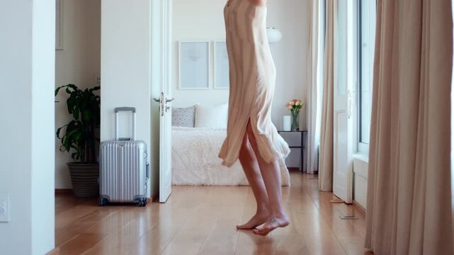 Travel, fun and woman on bed with jumping, getaway optimism and happiness on summer holiday. Smile, suitcase or person in hotel room with good time, vacation enjoyment or playful energy in bedroom.