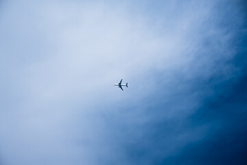 Fototapeta premium Plane flying through blue sky with clouds in the background on a clear day