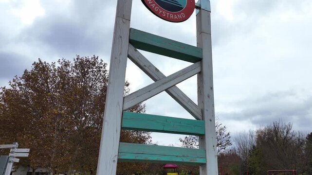 Looking up at the logo of the public beach in Zam&aacute;rdi, Hungary. Cloudy autumn day at the Lake Balaton. Slow motion tilt up view with quiet, off season atmosphere.