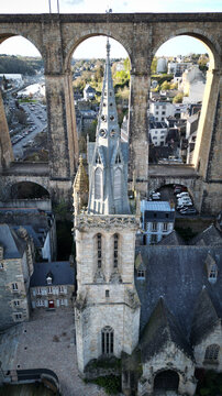 Aerial view of Eglise Saint-Melaine de Morlaix spire framed by the massive arches of the historic stone viaduct in Morlaix, Bretagne, France.