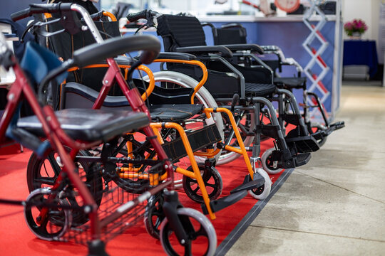 Wheelchairs Displayed at Medical Equipment Exhibition. Rows of wheelchairs and mobility aids displayed on a red carpet at a healthcare trade show or medical equipment expo.