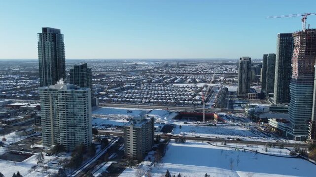 Skyscraper condominiums under construction in downtown Mississauga, Ontario, Canada. Aerial, shot moving in a circular pattern, on a winter afternoon in December, 2021.