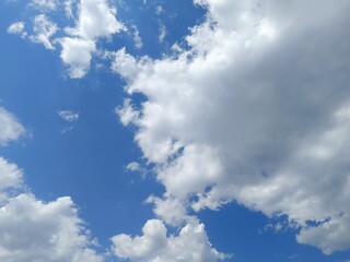 Obraz premium Large dense white and grey clouds in a blue sky. Dynamic summer weather skyscape background