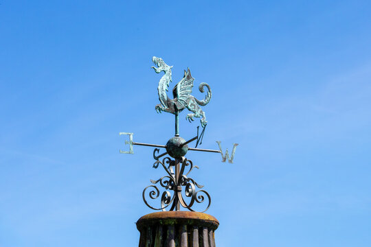 Dragon weather vane, wind vane, weathercock pointing toward the East. Wind direction instrument, with letters for compass points. 