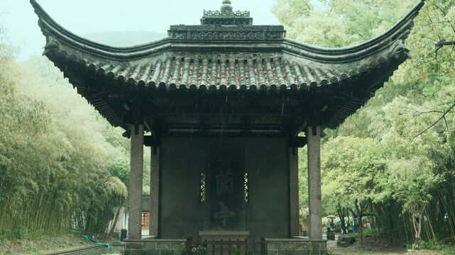 Traditional Chinese pavilion surrounded by bamboo forest in the rain