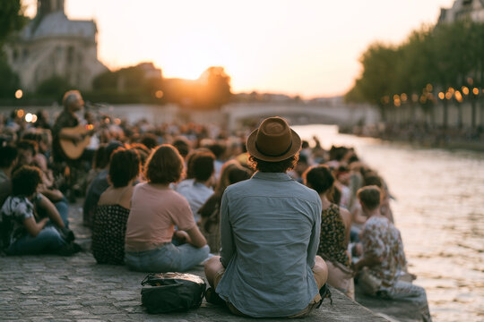 Crowd watching an outdoor riverside concert during Fete de la Musique in France at sunset, illustrating live music, summer celebration, and festive urban atmosphere